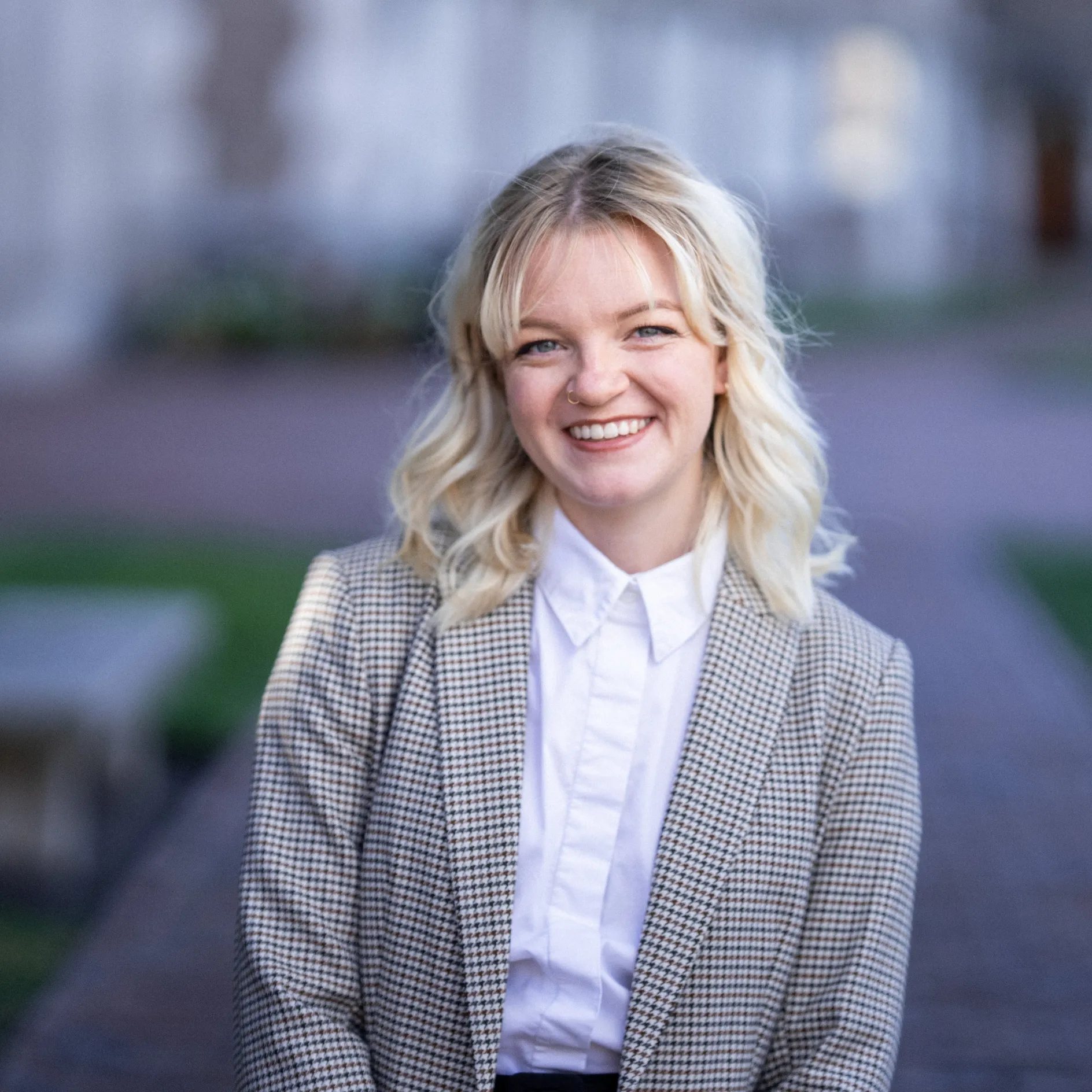 Willden smiling to the camera with her arms crossed behind in a campus background